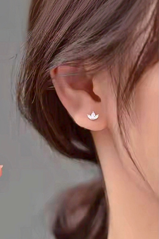 Close-up of an ear wearing a small silver earring with a floral design.